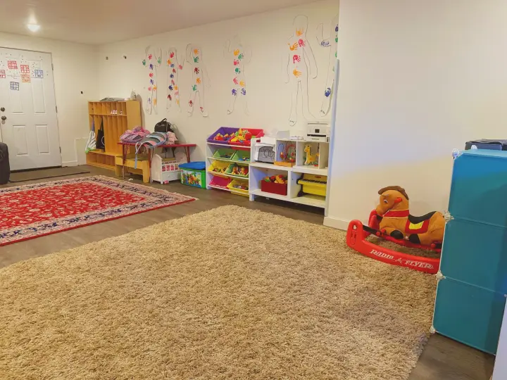 Spacious carpeted playroom with cubbies and organized toys in the Lynnwood home daycare