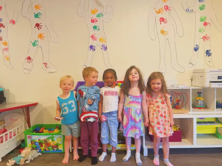 Children standing together in the playroom at Angel Family Daycare