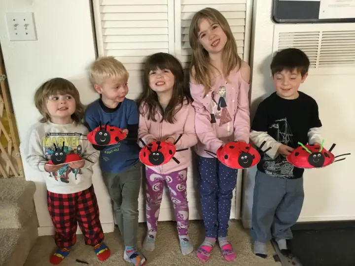 Smiling children holding ladybug craft projects at Angel Family Daycare
